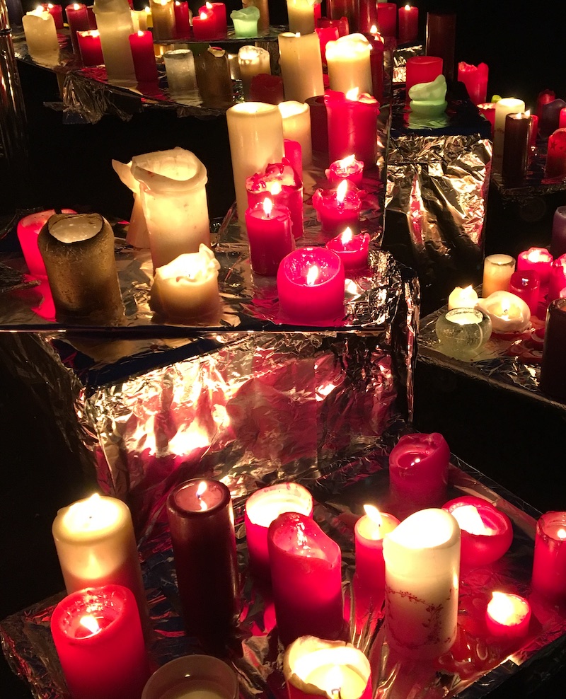 Kerzenmeer im warmen Licht, symbolische Verbindung zu Ahnen und Ritualarbeit